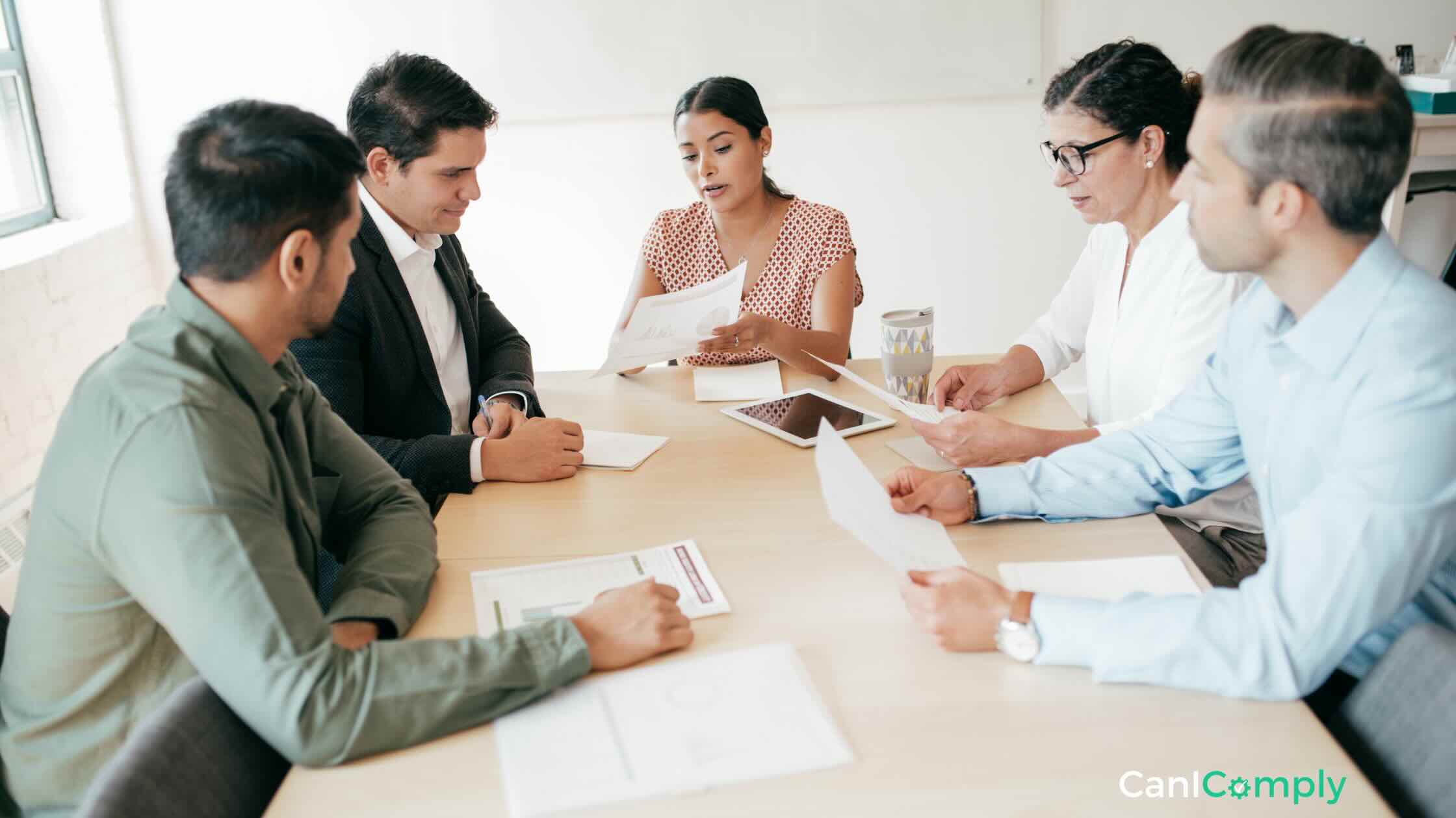 Team of five people gathered on the table to discuss a document